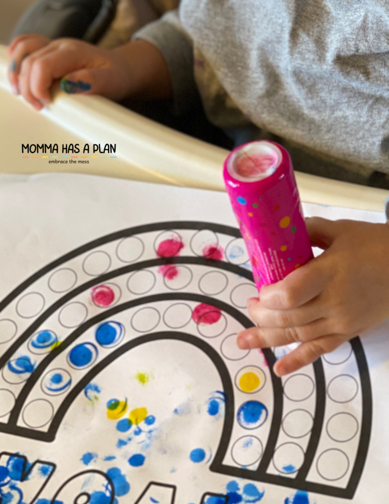 one-year-old creating a rainbow with do-a-dot markers