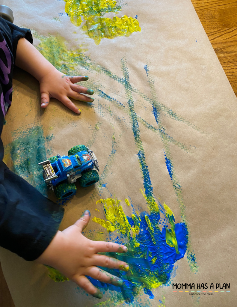 One year old painting on kraft paper with blue and yellow paint.