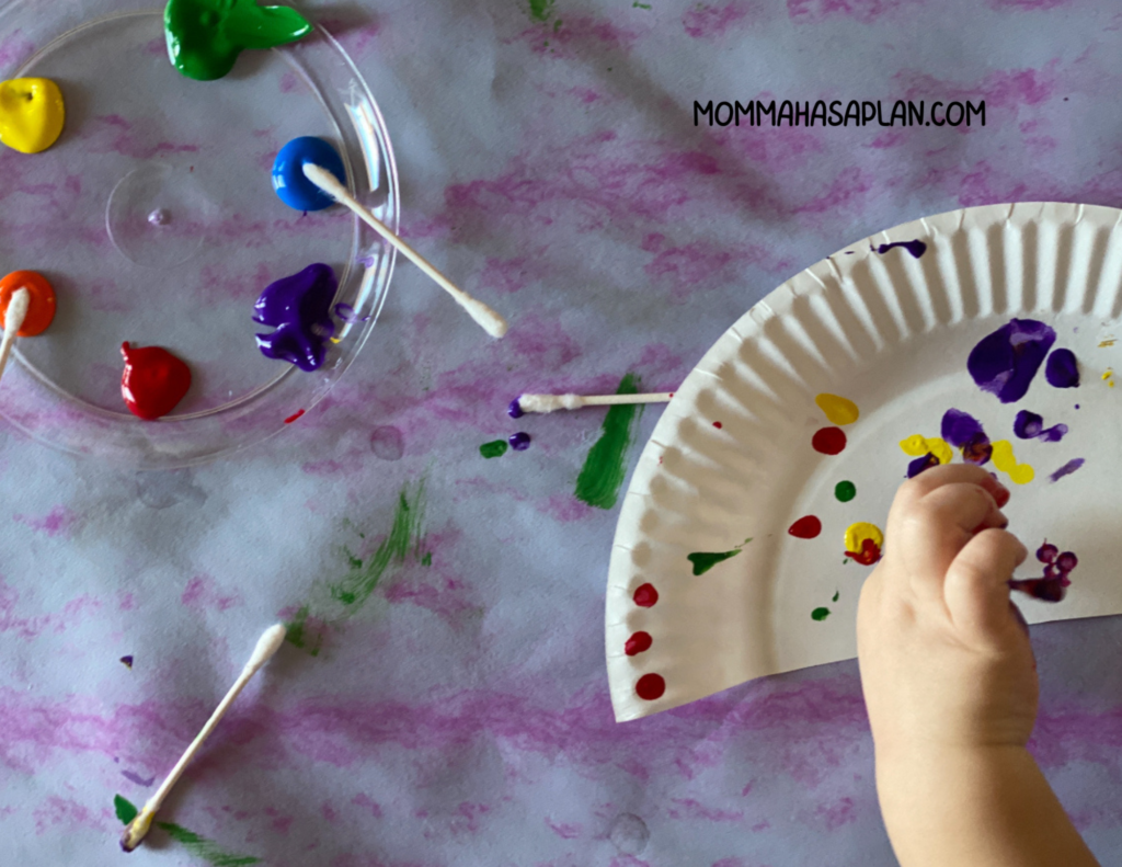 1-year-old using cotton swab to paint half a paper plate