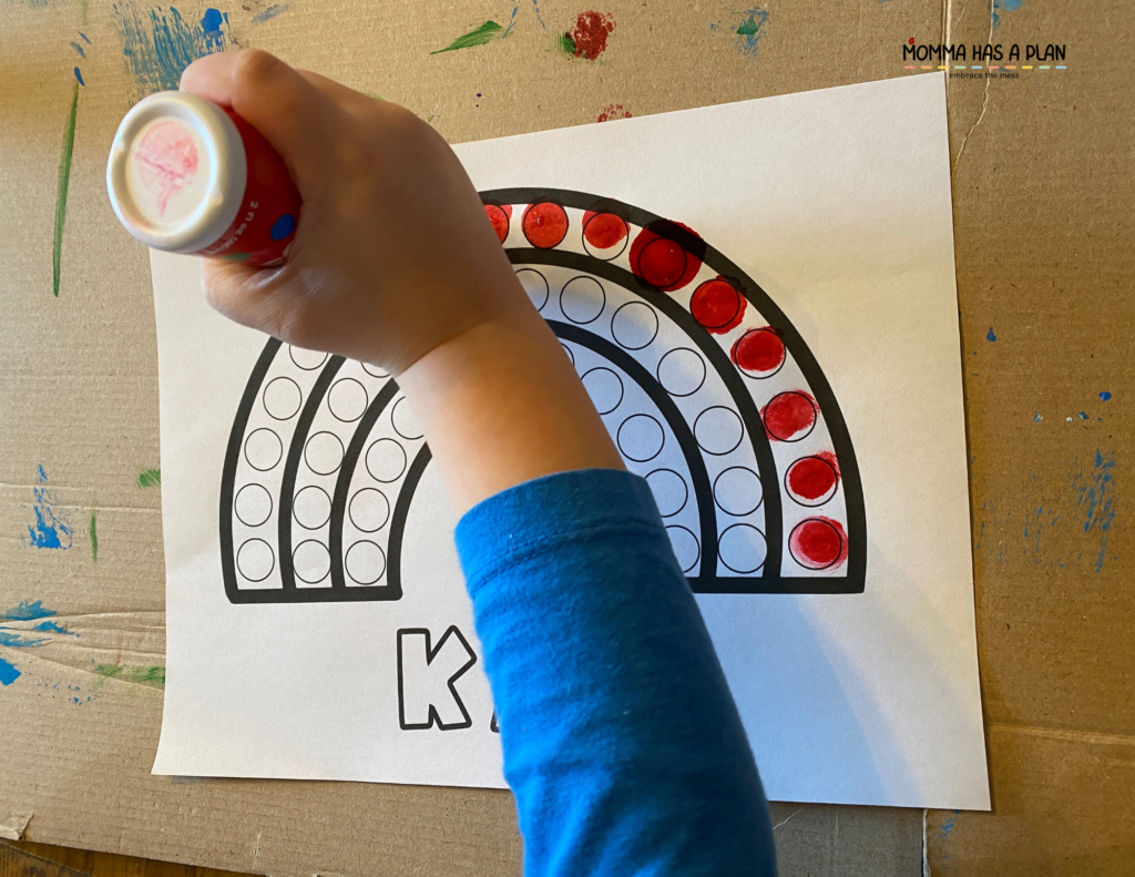 4-year-old using do-a-dot markers to create a rainbow